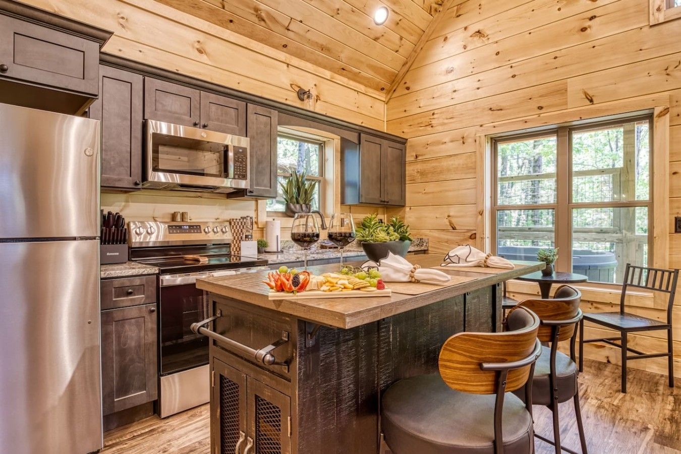 Una cocina moderna con electrodomésticos de acero inoxidable, armarios de madera y una isla central con taburetes de bar.