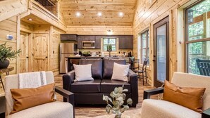 A cozy cabin interior with a wooden ceiling, a kitchen area, and a seating area with a couch and chairs. - Twilight Escape | Designer Cabin + Firepit & Views (Sevierville)