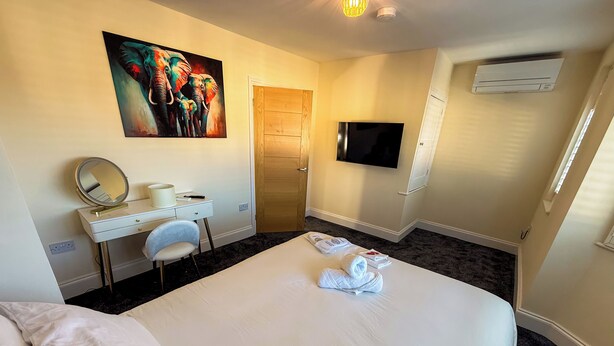 Une chambre d’hôtel avec un lit, un bureau doté d’un miroir, une télévision et un tableau accroché au mur.