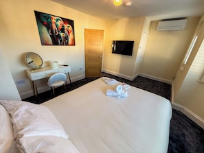 Une chambre d’hôtel avec un lit, un bureau doté d’un miroir, une télévision et un tableau accroché au mur.