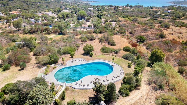 An aerial view of a resort with a swimming pool, surrounded by greenery and a mountainous backdrop. - 'Istana' Apartment with Shared Pool, Wi-Fi, and Air Conditioning (Porto Istana)