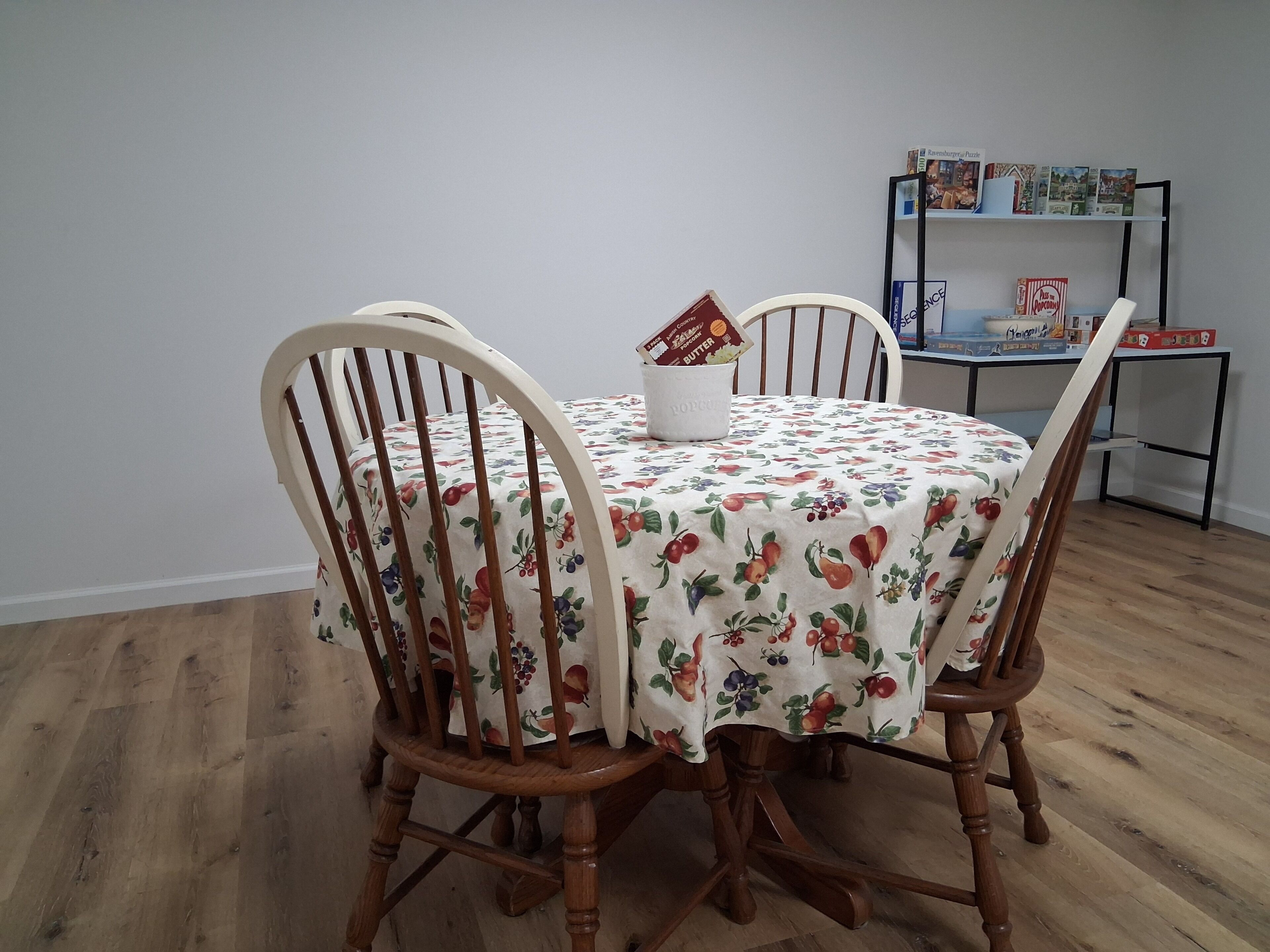 A dining table with a floral tablecloth, surrounded by wooden chairs.