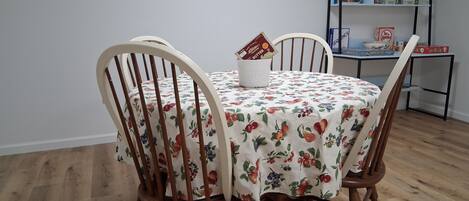 A dining table with a floral tablecloth, surrounded by wooden chairs.