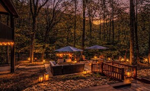Una terraza con mobiliario exterior, una pérgola con luces de cuerda y una cerca de madera.
