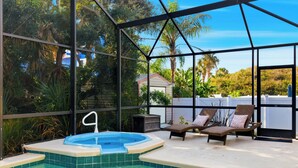 A swimming pool with a hot tub, lounge chairs, and a glass enclosure with a view of the surrounding greenery. - 2 Homes • 2 Pools • Sleeps 21 • Across from Beach (Saint Augustine)