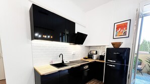 Una cocina compacta con armarios negros, un lavamanos, un microondas y un refrigerador.
