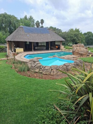 A house with a pool, surrounded by rocks and grass. - The Address Luxurious (Johannesburg)