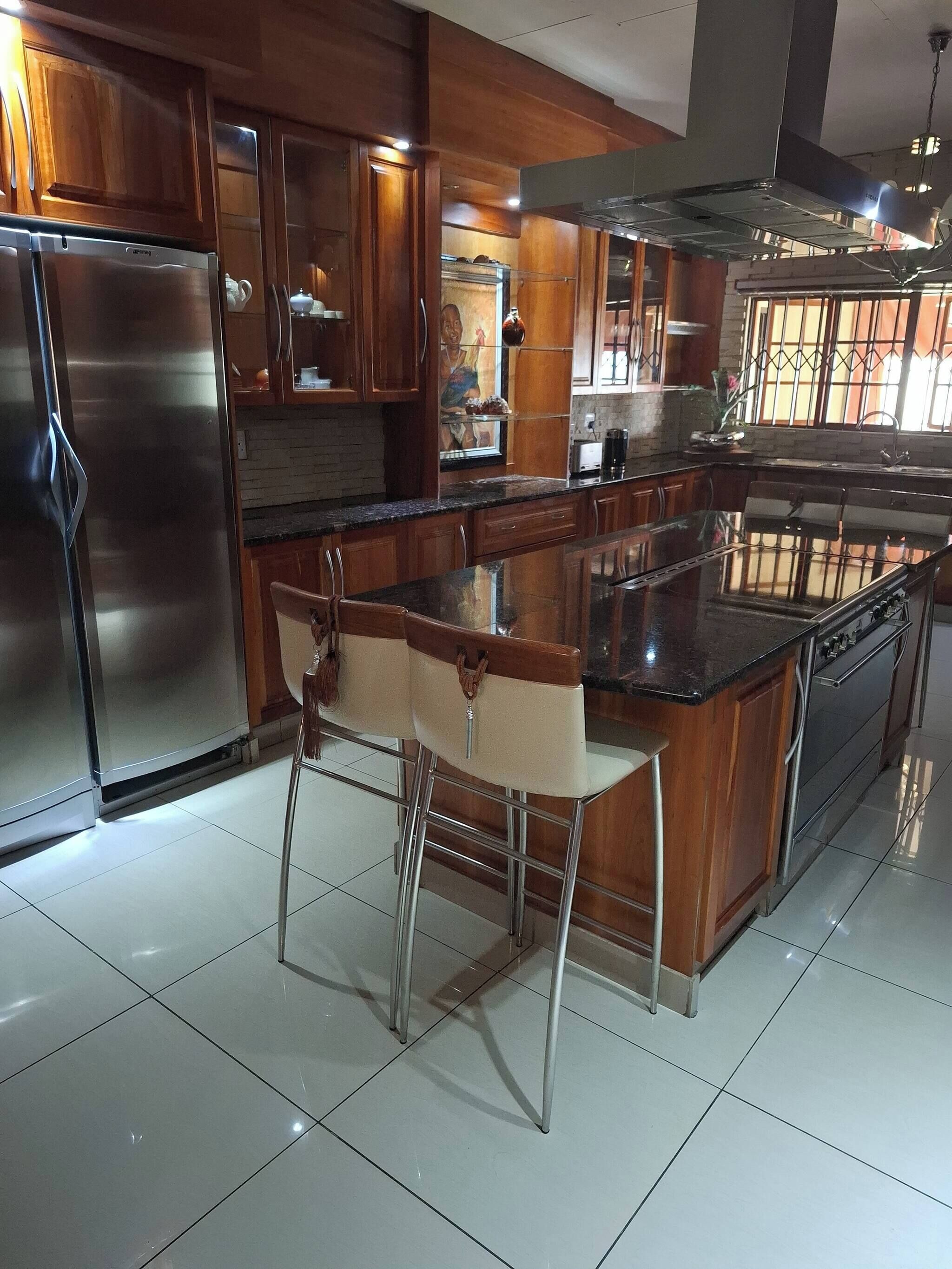 Een moderne keuken met roestvrijstalen apparatuur, houten kasten en een centraal eiland met barstoelen.