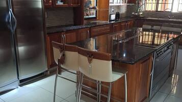 Een moderne keuken met roestvrijstalen apparatuur, houten kasten en een centraal eiland met barstoelen.