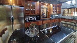 A kitchen with wooden cabinets, a stainless steel refrigerator, a microwave, a stove, and a decorative glass bowl. - The Address Luxurious (Johannesburg)