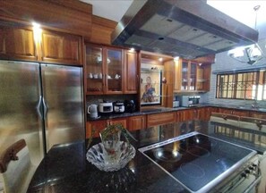 A kitchen with wooden cabinets, a stainless steel refrigerator, a microwave, and an induction cooktop. - The Address Luxurious (Johannesburg)
