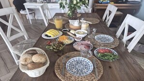 A wooden dining table with plates of food, a basket of bread, and a vase of flowers. - Agritourism, family studio. (Ładzin)