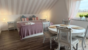 A bedroom with a bed, bedside tables, a dining table with chairs, and a window with a view. - Agritourism, family studio. (Ładzin)