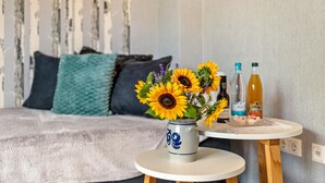 A bed with a grey blanket, a teal pillow, and a vase with sunflowers on a small round table. - Apartment "Weinbergschnecke" with Private Terrace and Wi-Fi (Efringen-Kirchen)