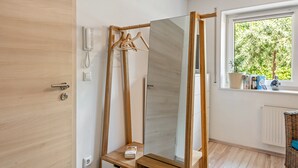 A room with a wooden door, a telephone, a mirror with a wooden frame, a window with a view of greenery, and a radiator. - Apartment "Weinbergschnecke" with Private Terrace and Wi-Fi (Efringen-Kirchen)