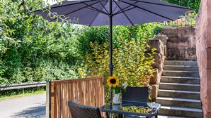 A patio with a table and chairs, a large umbrella, and a staircase leading to a higher level. - Apartment "Weinbergschnecke" with Private Terrace and Wi-Fi (Efringen-Kirchen)