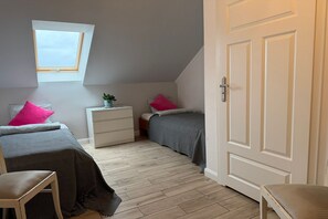A bedroom with two beds, a nightstand, a chair, a window, and a door.