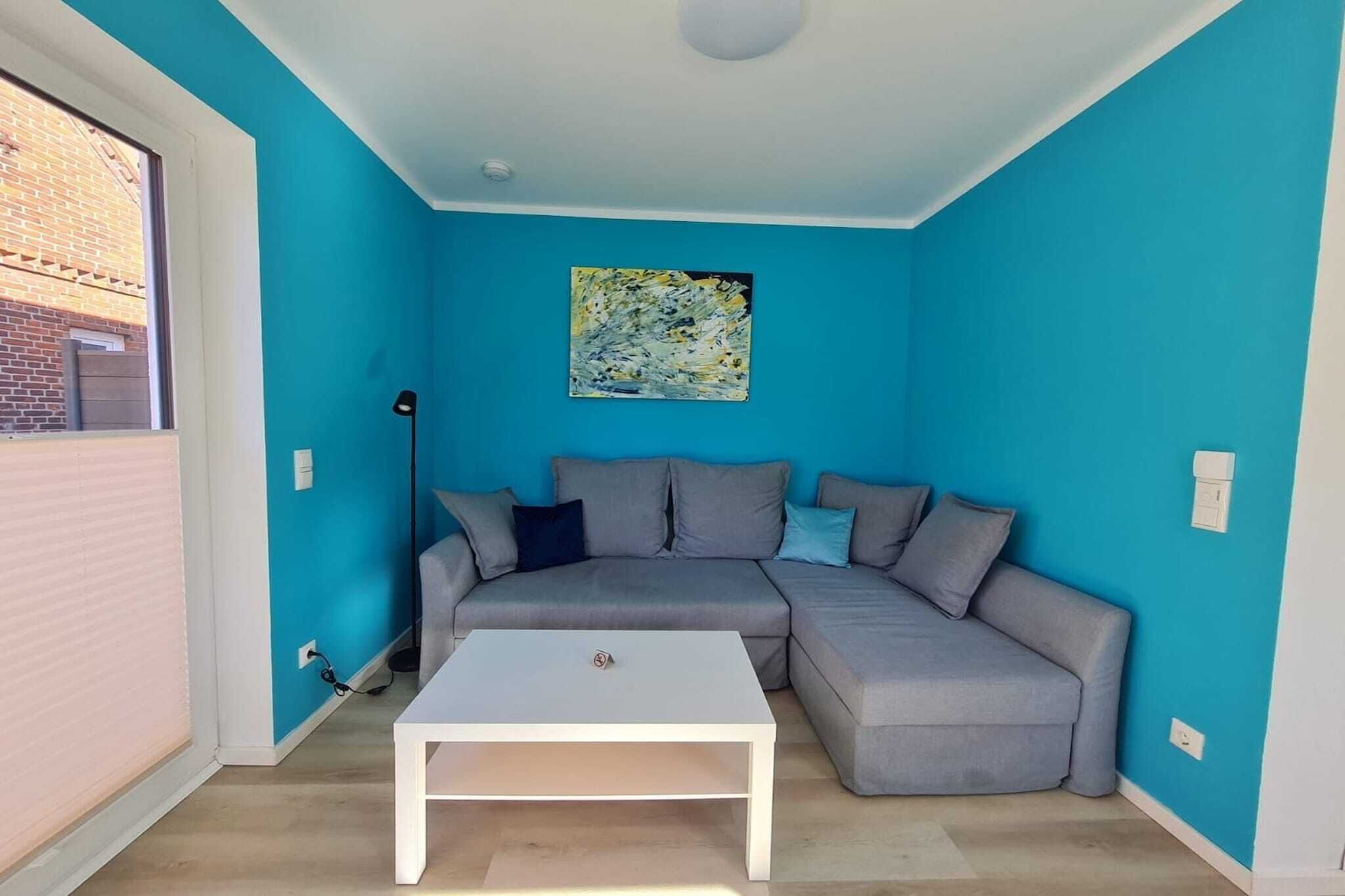 A room with a blue wall, a grey sectional sofa, a white coffee table, and a floor lamp.