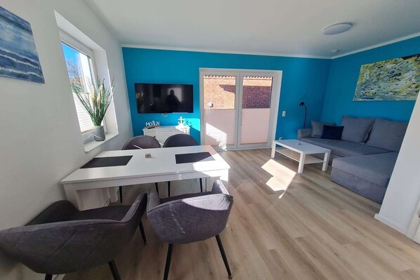 Un espacio moderno con comedor, sofá y televisor.