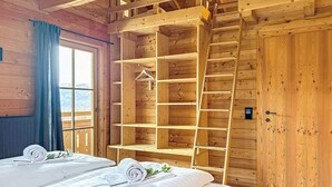 Habitació de fusta amb un llit, un armari de fusta i una finestra amb vista.