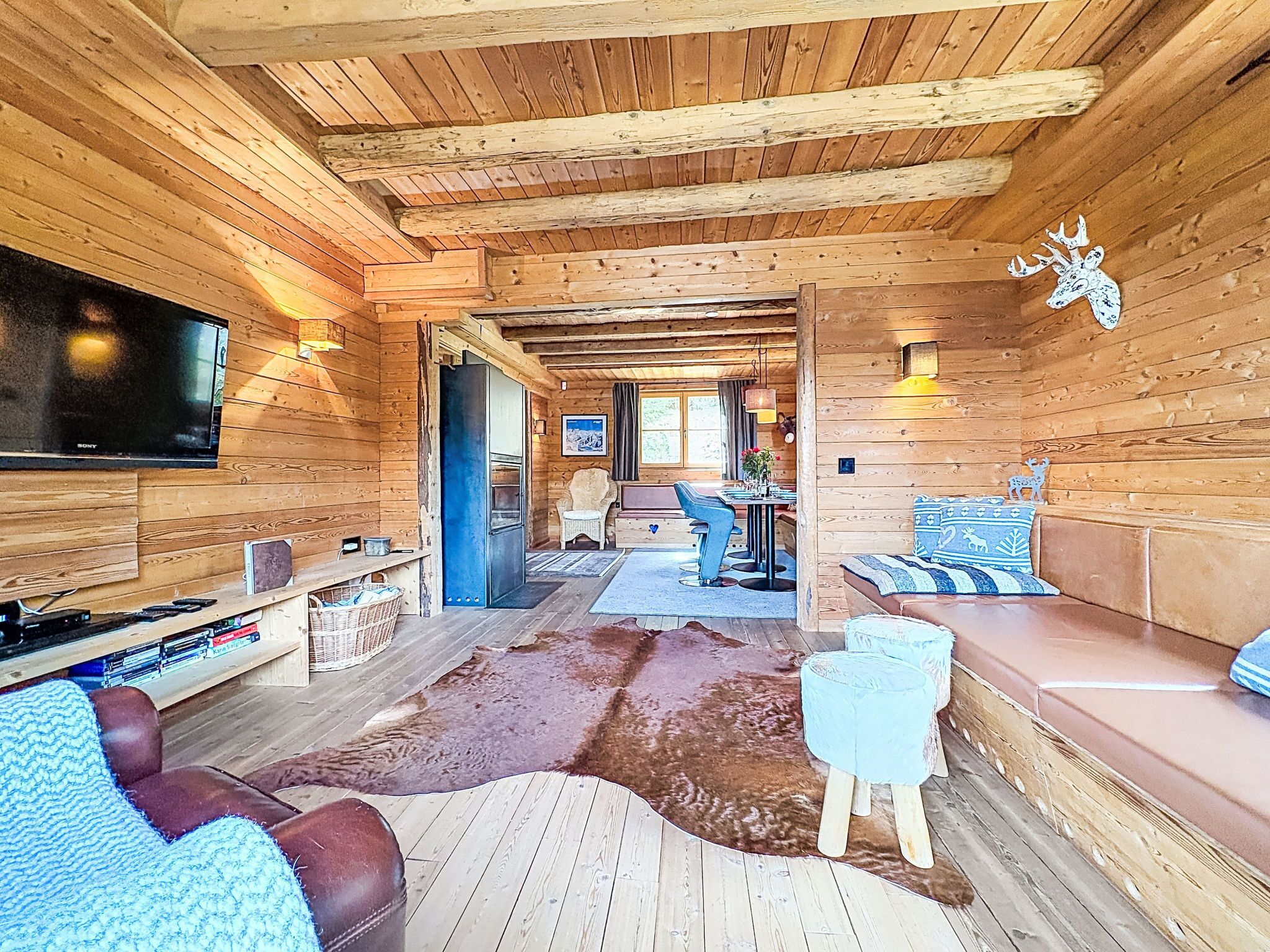 A log cabin interior with a television, seating area, and a dining table.
