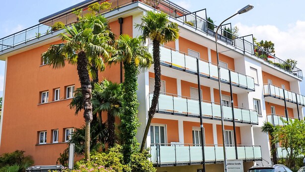 A multi-story building with balconies, palm trees, and a clear sky. - Residenza Corallo by Interhome (Ascona)