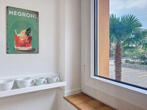 A room with a window, a shelf with white cups, and a wall-mounted sign reading 'NEGRONI'. - Residenza Corallo by Interhome (Ascona)