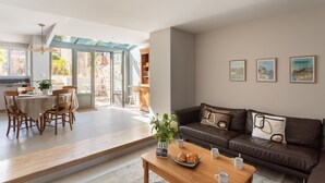 Una sala moderna con un sofá de cuero marrón, una mesa de centro de madera y un comedor con una mesa y sillas.