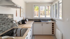 Una cocina moderna con estufa negra, armarios blancos y ventana con vista a un jardín.