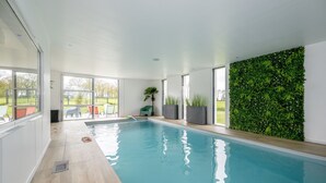 Ein Hallenbad mit Holzboden, großen Fenstern und einer grünen Wand.