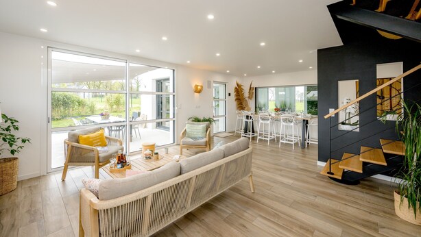 Ein modernes Wohnzimmer mit Sofa, Essbereich und Treppe.