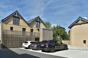A residential building with a garage, parked cars, and a clear sky. - Résidence Des Champs sur Mer - À 400 m de la plage (Dinard)