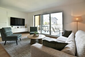 A modern living room with a sofa, armchair, and a coffee table. - Résidence Des Champs sur Mer - À 400 m de la plage (Dinard)