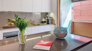 A modern kitchen with white cabinets, a stainless steel sink, a vase with flowers, a bowl, and a menu on the counter. - Residenza Eride - Apt.4 by Interhome (Locarno)