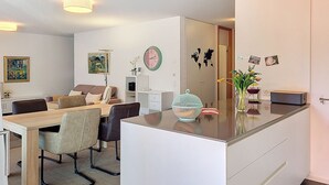 A modern living room with a dining area, a large mirror, and a kitchen counter. - Residenza Eride - Apt.4 by Interhome (Locarno)