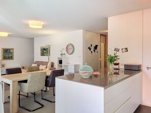 A modern living room with a dining area, a large mirror, and a kitchen counter. - Residenza Eride - Apt.4 by Interhome (Locarno)