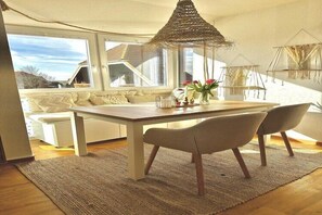 A modern dining area with a table, chairs, and a hanging light fixture. - Ferienwohnung in Lemkenhafen für 3 Gäste (Lemkenhafen)