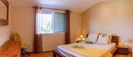 A bedroom with a wooden bed, a desk, a chair, and a window with curtains.