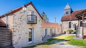 En byggnad av sten med en balkong, en kyrka med ett klocktorn och en stenlagd innergård.
