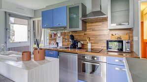 Eine moderne Küche mit blauen Schränken, einem Edelstahl-Geschirrspüler, einem Backofen und einer Mikrowelle.
