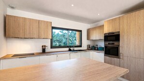 Eine moderne Küche mit Holzschränken, einem großen Fenster und integrierten Geräten.