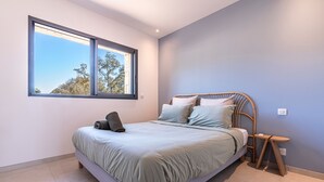 Ein modernes Schlafzimmer mit einem Bett, einem Fenster und einem Nachttisch.