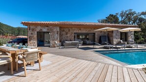 Ein Steingebäude mit Pool, Sitzgelegenheiten im Freien und einer Holzterrasse.