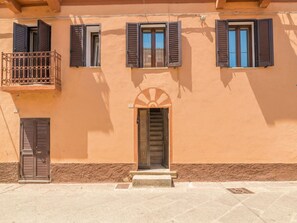A building with three windows, one with a balcony, and a door with a decorative arch. - Nuraghi by Interhome (Arzachena)