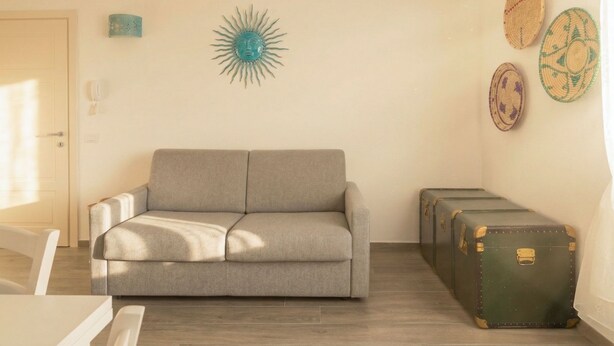 Ein Wohnzimmer mit einer Couch, einem Wandbild und einem Koffer.
