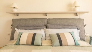 Ein Bett mit einer Decke, zwei Kissen, einem Kopfteil und zwei Wandlampen.