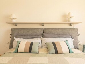 A bed with a quilt, two pillows, a headboard, and two wall-mounted lamps. - Nuraghi by Interhome (Arzachena)
