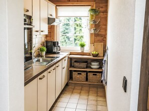 A compact kitchen with a window, wooden cabinets, a coffee maker, and a potted plant. - Ferienwohnung Belan by Interhome (Klippitztörl)