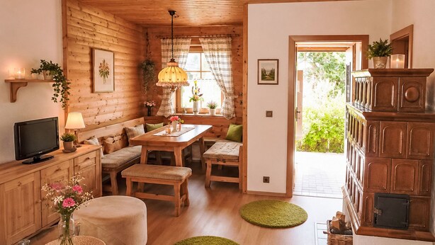 Interior acolhedor de uma cabana, com decoração em madeira, área de refeições, televisão e lareira.