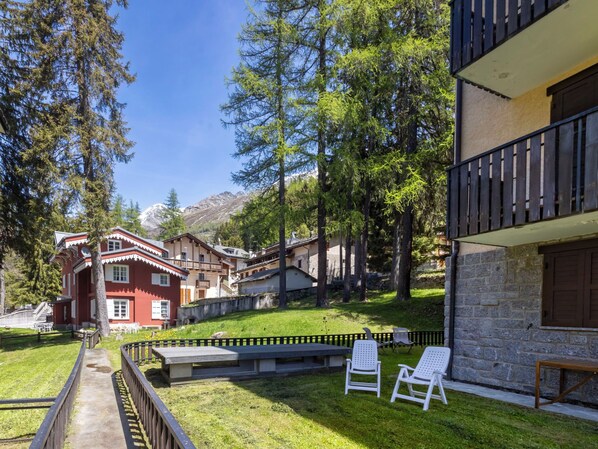 A traditional chalet with a stone facade, a balcony, and a grassy yard with two white lounge chairs. - Villa Adele by Interhome (Madesimo)